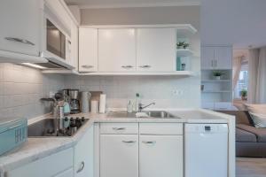 a kitchen with white cabinets and a sink at Waterkant in Husum +3 photos