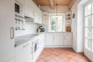 a kitchen with white cabinets and a tile floor at Ferienhaus Geest auf Föhr in Borgsum