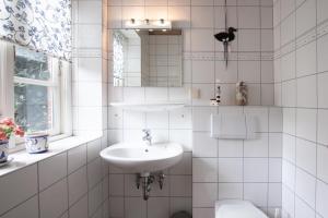 a white bathroom with a sink and a toilet at Ferienhaus Geest auf Föhr in Borgsum