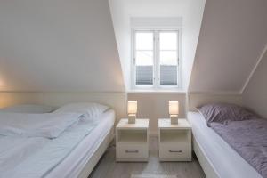 BorgsumにあるFerienhaus Geest auf Föhrのベッド2台、ランプ2つ(テーブル付)が備わる客室です。