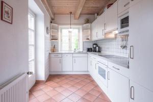 eine Küche mit weißen Schränken und Fliesenboden in der Unterkunft Ferienhaus Marsch auf Föhr in Borgsum