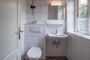 a white bathroom with a toilet and a sink at Ferienhaus Marsch auf Föhr in Borgsum