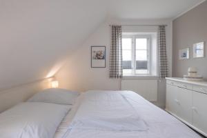 a white bed in a bedroom with a window at Ferienhaus Marsch auf Föhr in Borgsum