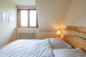 a bedroom with a bed and a lamp and a window at Ferienwohnung in Borgsum (oben rechts) in Borgsum