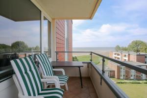 - deux chaises assises sur un balcon avec vue sur l'océan dans l'établissement Strandperle, à Wyk auf Föhr