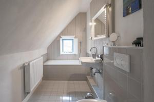 ein weißes Bad mit einem Waschbecken und einem Fenster in der Unterkunft Stadthuus 51 in Husum
