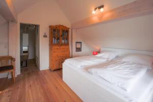 um quarto com uma cama branca e piso em madeira em Haus Inge em Dagebüll