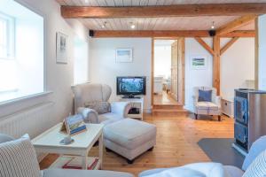 ein Wohnzimmer mit einem Sofa und einem TV in der Unterkunft Wellnesswarft Waygaard Ost in Dagebüll