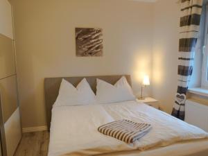 a white bed with a blanket on top of it at Apartment Godewind in Dagebüll