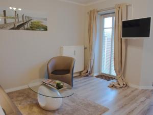 a living room with a glass table and a chair at Apartment Godewind in Dagebüll