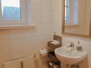 ein weißes Badezimmer mit einem Waschbecken und einem Spiegel in der Unterkunft Apartment Godewind in Dagebüll