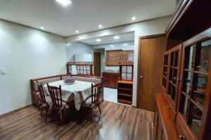 ein Esszimmer mit einem Tisch und einer Küche in der Unterkunft Ap. de 4 quartos com ar condicionado a 150m da Rua Coberta in Gramado