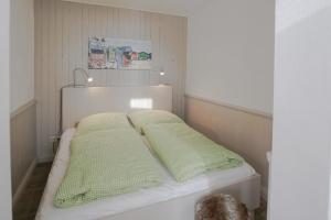 uma cama com almofadas verdes num quarto em Ferienhaus vor Rügen em Sundhagen-Niederhof