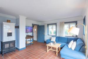 ein Wohnzimmer mit einem blauen Sofa und einem Kamin in der Unterkunft Reethus Ulla in Husum