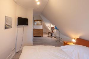a bedroom with a bed and a tv on the wall at Reethus Ulla in Husum