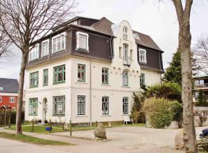 une grande maison blanche avec un toit noir dans l'établissement Apartment Roock, à Wyk auf Föhr