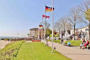 un parc avec trois drapeaux et des personnes assises sur des bancs dans l'établissement Apartment Roock, à Wyk auf Föhr