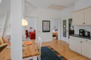 a kitchen and living room with white cabinets and a table at Woldsen in Husum