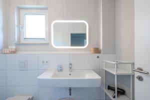a white bathroom with a sink and a mirror at Ankerzeit in Husum +2 photos