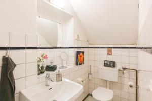 フーズムにあるKleine Stubeの白いバスルーム(洗面台、トイレ付)