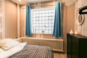 フーズムにあるKleine Stubeのベッドルーム1室(ベッド1台、青いカーテン付きの窓付)
