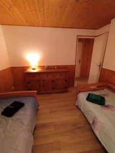 a bedroom with two beds and a dresser with a light at Appartement Daria in Prémanon