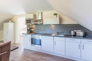 a kitchen with white cabinets and stainless steel appliances at Schobüller Seestern in Husum