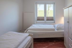 twee bedden in een kamer met een raam bij Altes Schäferhaus in Nordstrand