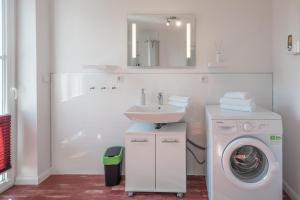 ein Badezimmer mit einer Waschmaschine und einem Waschbecken in der Unterkunft Altes Schäferhaus in Nordstrand