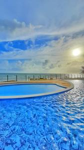 ein Pool neben einem Strand mit dem Meer in der Unterkunft Chalé condomínio beira mar em Zumbi Beach Resort in Rio do Fogo
