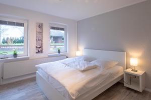 a white bedroom with a white bed and two windows at Krokusliebe in Husum