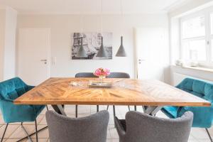 a dining room with a wooden table and blue chairs at Lütte Jung in Husum