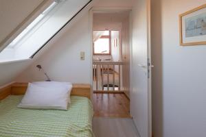 sypialnia na poddaszu z łóżkiem i oknem w obiekcie Käpt'n Cook 09 w mieście Nordstrand