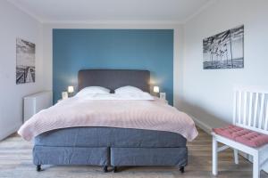 a bedroom with a large bed with blue walls at Wattlaeufer in Husum