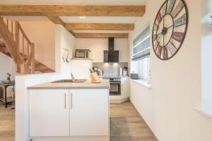 a kitchen with white cabinets and a large clock on the wall at Linas Huis in Galmsbüll