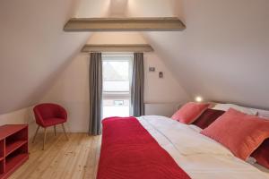 1 dormitorio con 1 cama grande y 1 silla roja en Haus Beltringharde, en Reußenköge