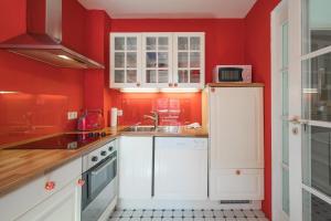 cocina con paredes rojas y armarios blancos en Dat lütte Huus - Wohnung 2, en Husum
