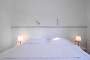 1 dormitorio con 1 cama blanca y 2 lámparas en Dat lütte Huus - Wohnung 2, en Husum