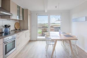 a kitchen with a table and chairs and a window at Reethus Backbord Dagebüll in Dagebüll