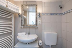 ein Badezimmer mit einem Waschbecken, einem WC und einem Spiegel in der Unterkunft Hannes Kapitänshaus in Husum