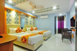 a hotel room with two beds and a television at Hotel New Majestic in Ajmer