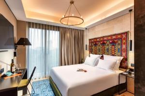 a hotel room with a large white bed and a desk at Brown Mamilla, a member of Brown Hotels in Jerusalem