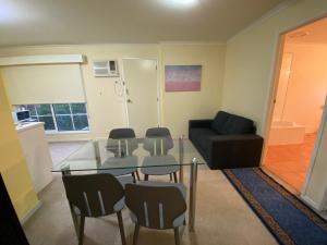 een woonkamer met een glazen tafel en stoelen bij Redwood Manor Motel Apartments in Warrnambool