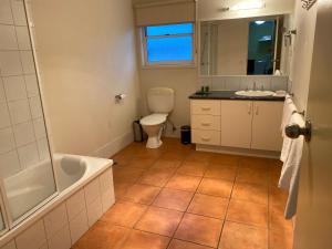 een badkamer met een bad, een toilet en een wastafel bij Redwood Manor Motel Apartments in Warrnambool