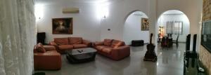 a living room with brown leather couches in a room at Residence Galaxy Togo in Lomé