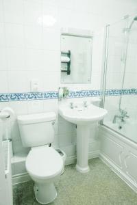 a white bathroom with a toilet and a sink at The Old Fourpenny Hotel in Warwick