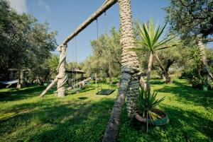 a rope swing in a park with a palm tree at Athena Studios in Vasilikos