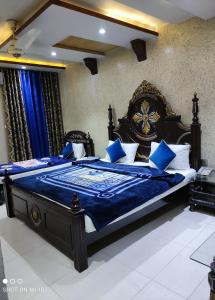 a bedroom with a large bed with blue sheets at Grand Palace Hotel in Lahore