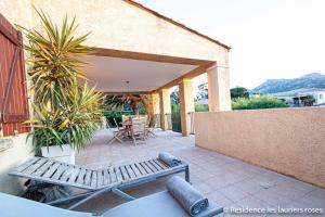 une terrasse avec deux bancs, une table et des chaises dans l'établissement Palmier appartement de vacances 3 chambres piscine commune chauffée, à Calvi