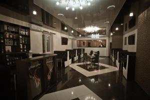 a restaurant with a bar with chairs and a chandelier at Elyzium Hotel Complex in Samara
